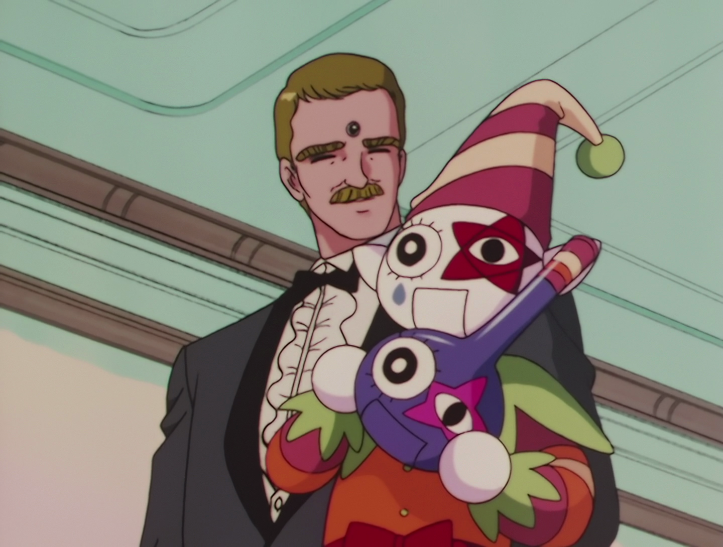 Dummy, a Lemures from the Sailor Moon SuperS special. He’s a small, clown-like ventriloquist dummy, so that’s two things I find unpleasant right there. He’s being held by a man wearing a dinner jacket, with the symbol of the Dead Moon - a black circle within a white circle - on his forehead. The Dummy is holding a decorated bottle.